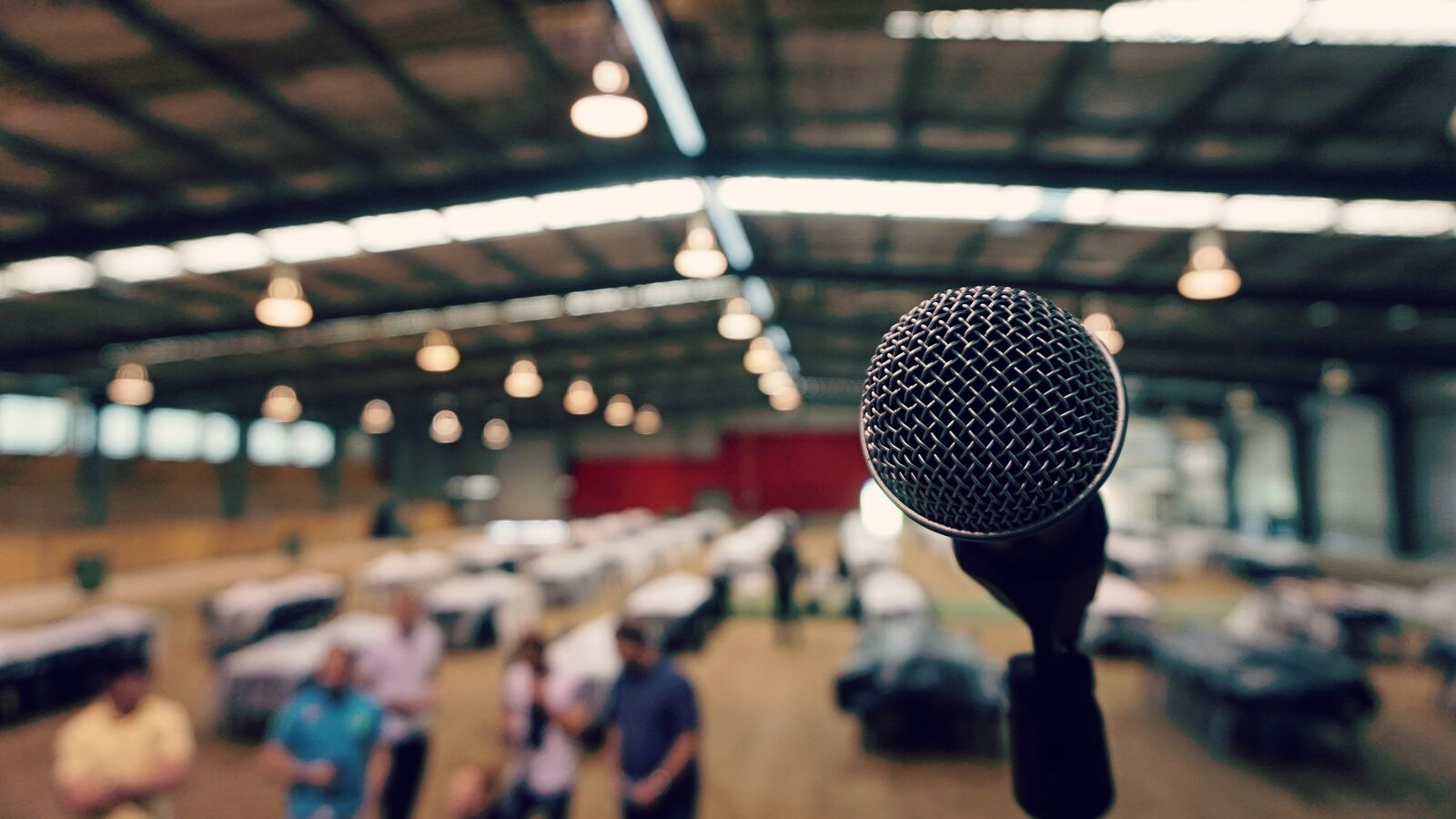 A microphone in the foreground of a large hall with a high ceiling and blurred people